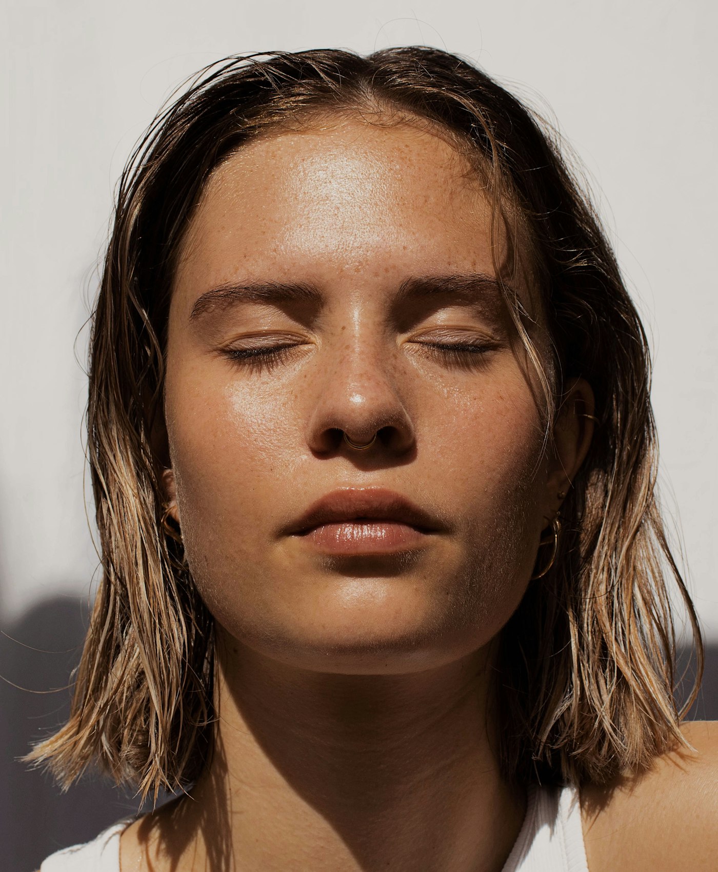 Mulher de olhos fechados com a pele iluminada pelo sol