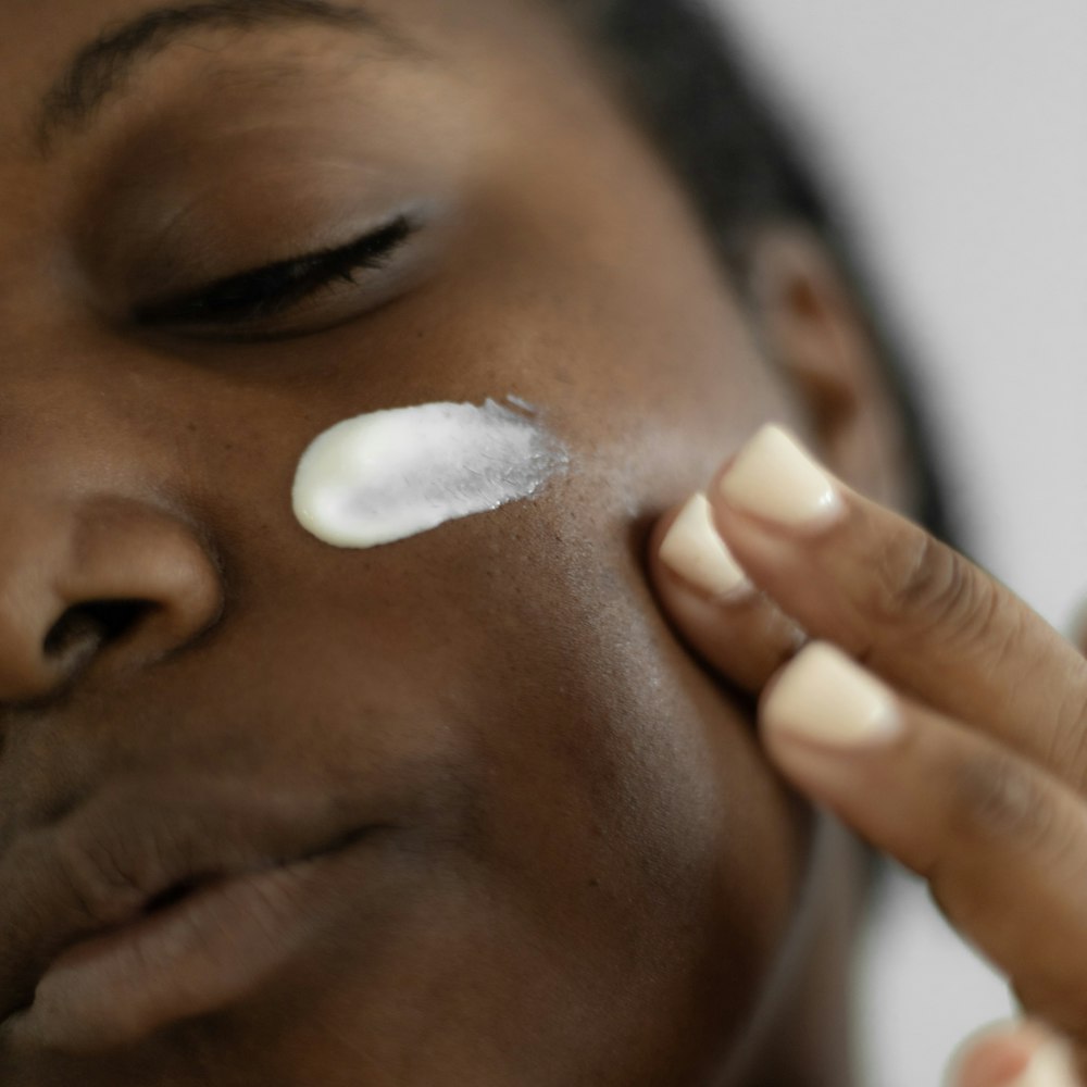 Mulher negra aplicando creme no rosto