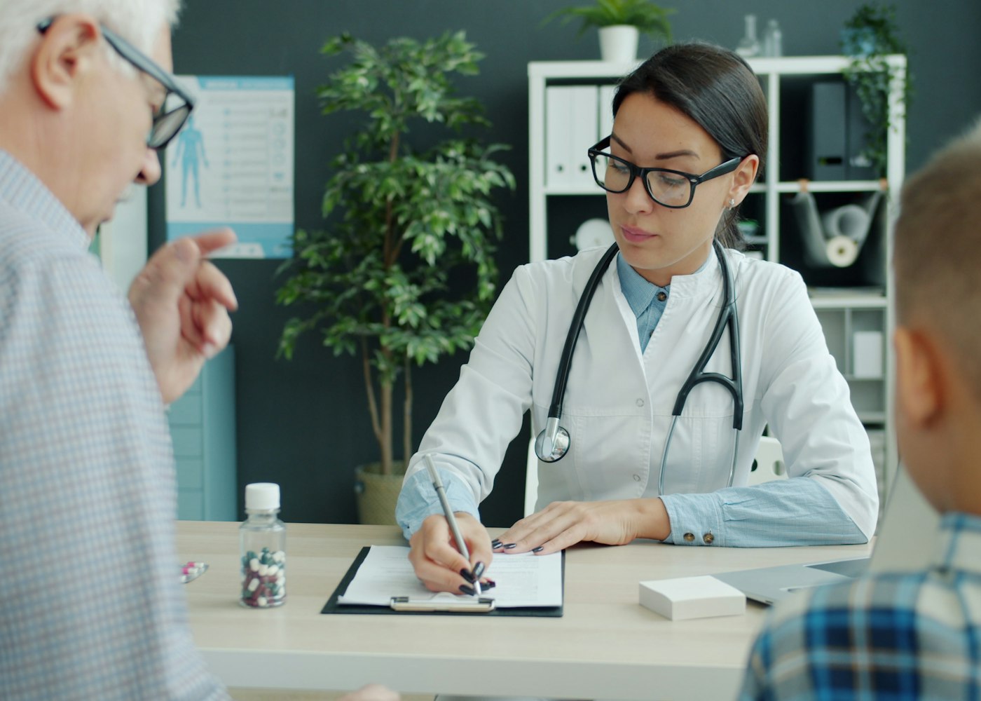 Médica atendendo pai e filho no consultório